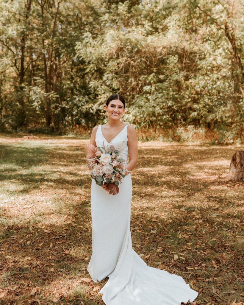 Bride holding a bouquet in a wooded outdoor setting