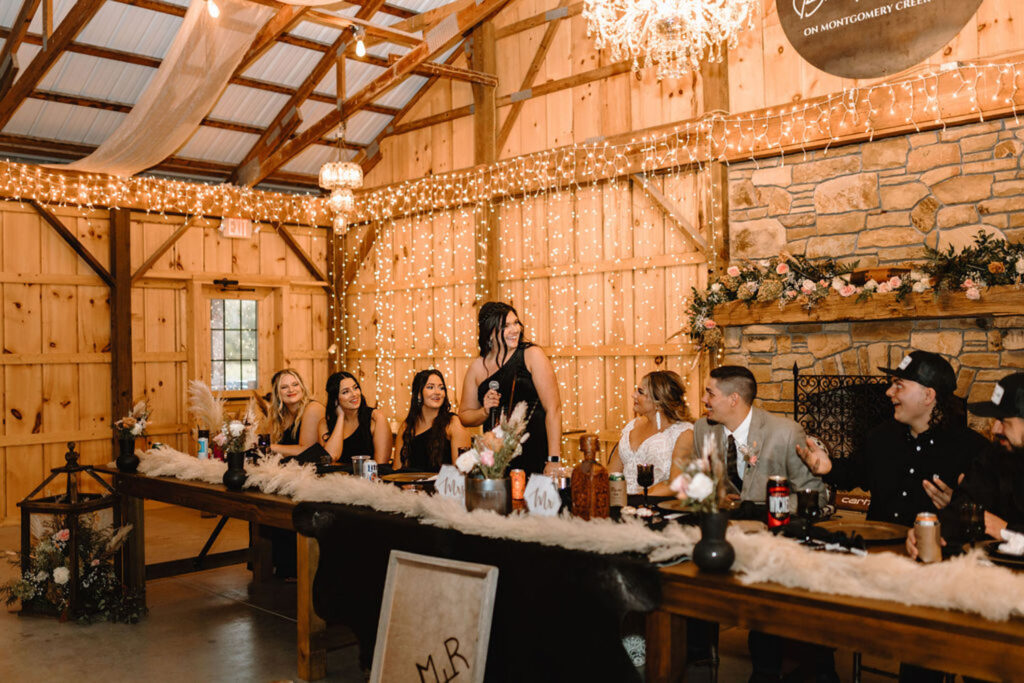 Wedding reception inside a barn with fairy lights and guests seated at a head table