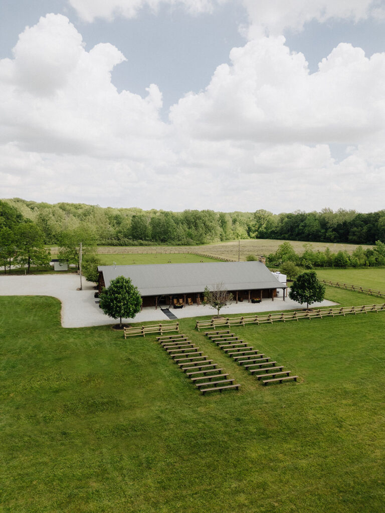 Outdoor ceremony setup at Montgomery Creek Ranch with rows of benches facing a barn in a green field