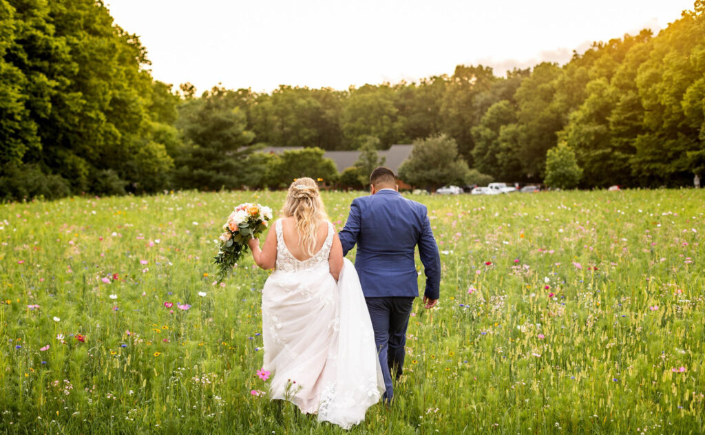 Bride and groom walking hand in hand through a wildflower field at Montgomery Creek Ranch