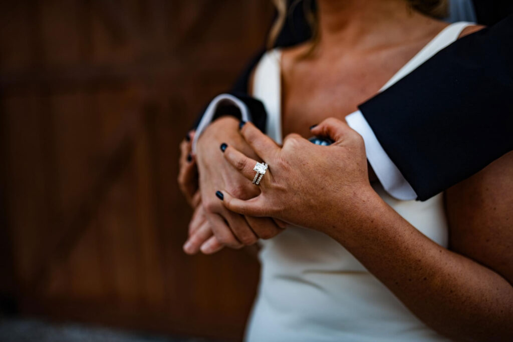 Close-up of a bride's hand showing her wedding ring while holding hands with her partner