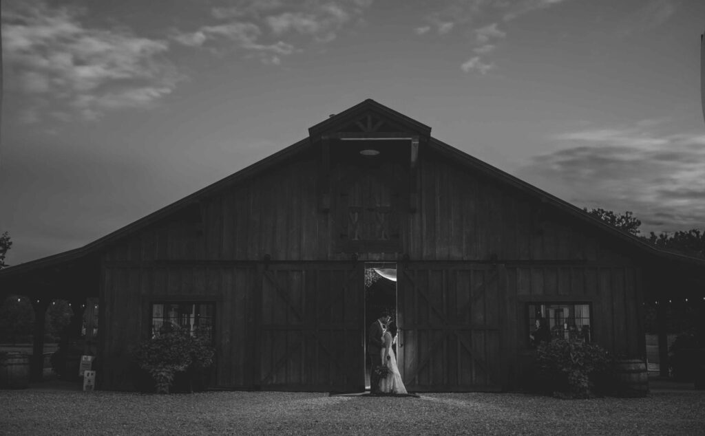 Bride and groom framed in the doorway of a rustic barn at dusk at Montgomery Creek Ranch