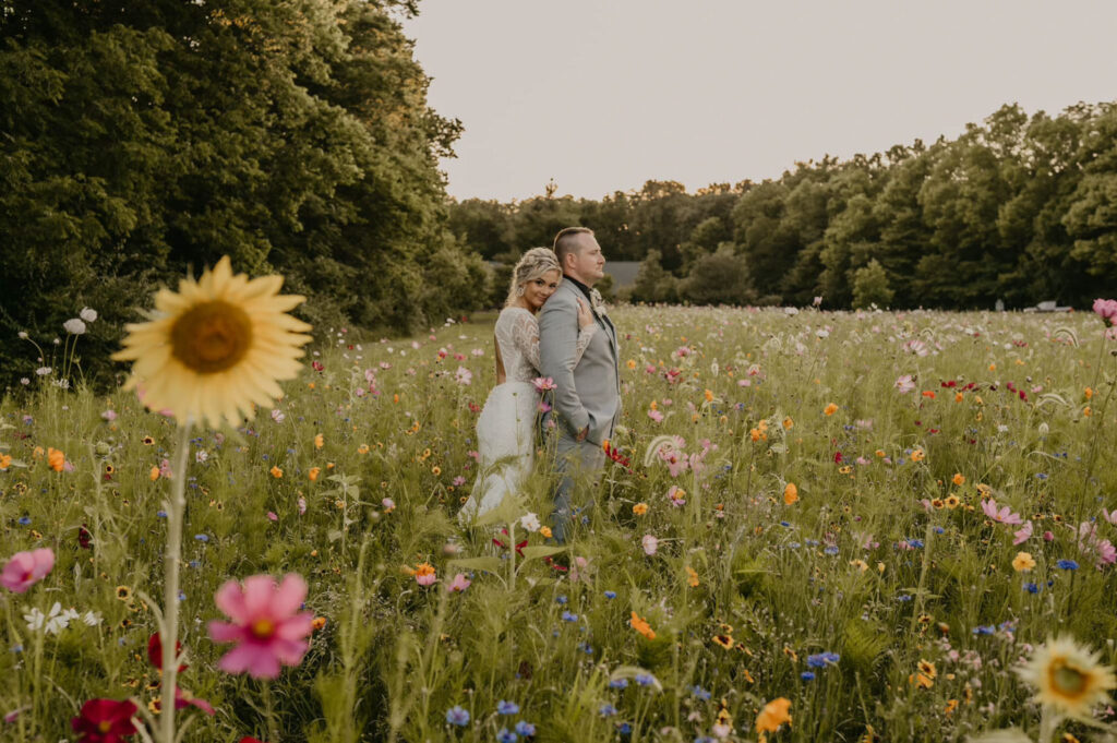 Bride and groom standing back-to-back surrounded by vibrant wildflowers