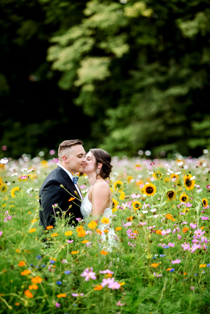 Bride and groom sharing a kiss in a wildflower meadow with sunflowers