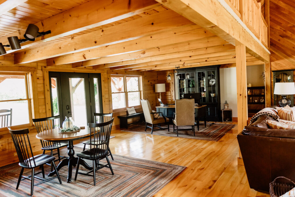 Dining and living area with wood-paneled walls and large windows