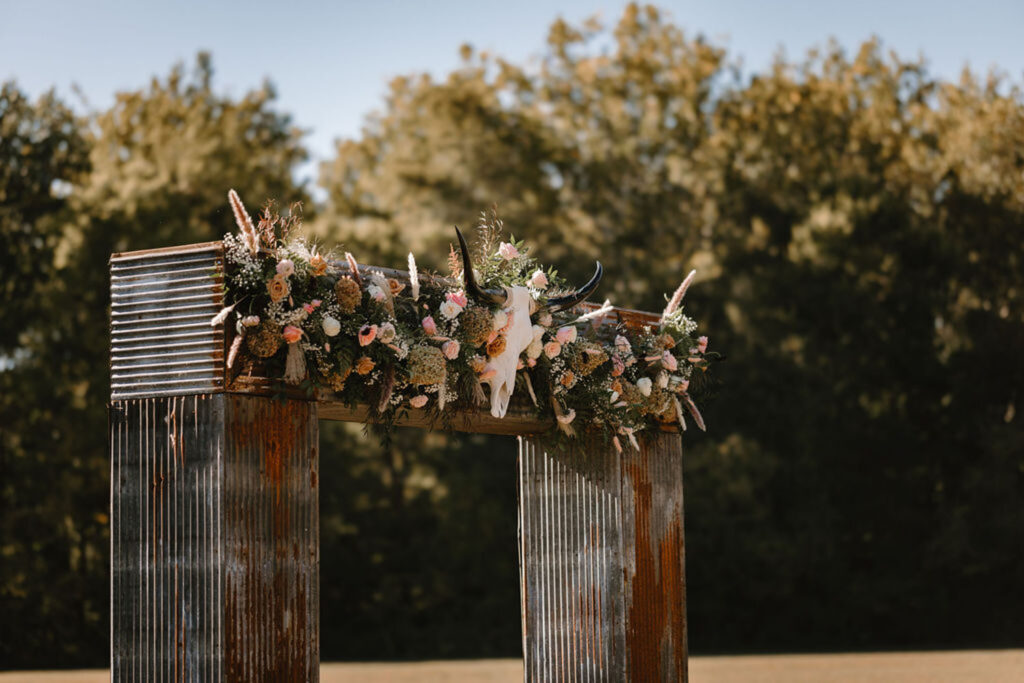 Rustic outdoor ceremony arch adorned with floral decor