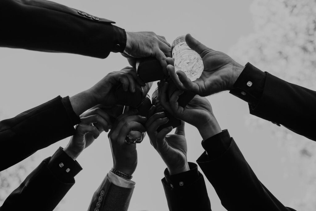 Group of hands raising drinks in celebration outdoors