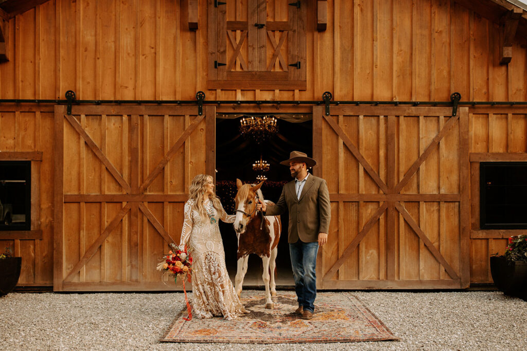 Couple with a horse in front of a rustic barn in a wedding location in Indianopolis