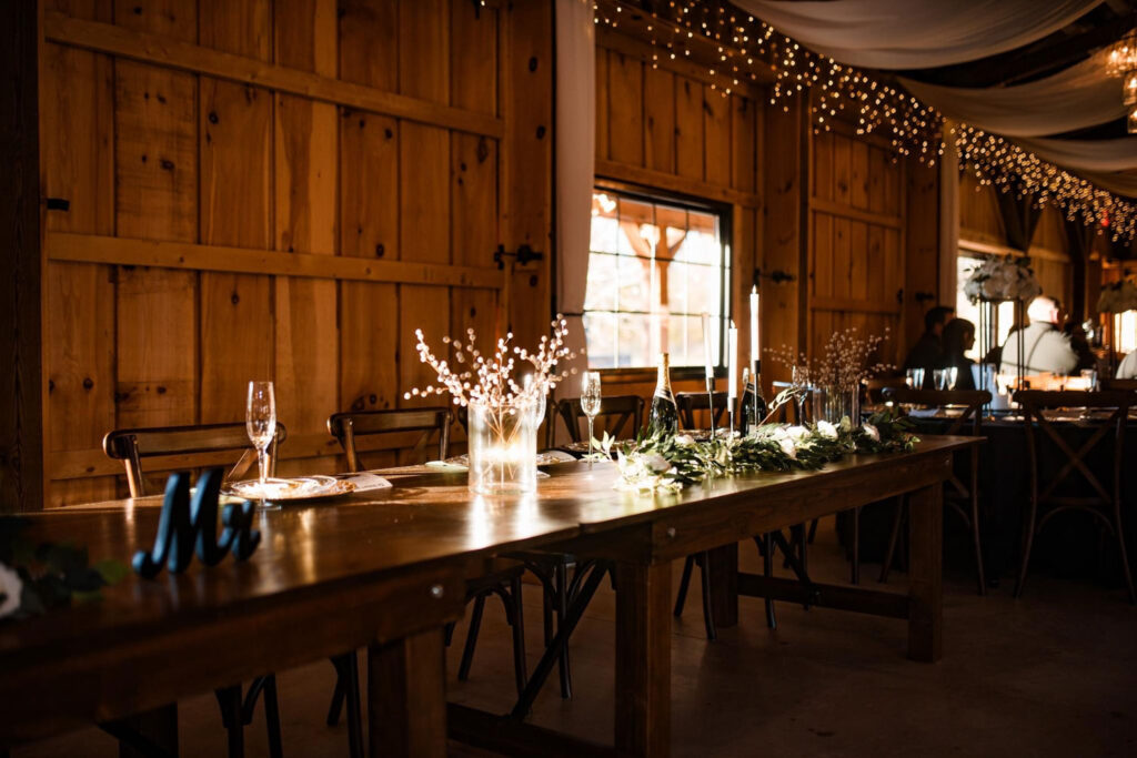 Rustic wooden reception table decorated with greenery and candles