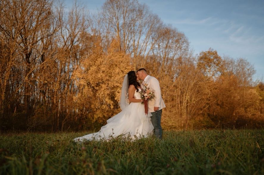 Couple sharing a kiss at sunset during their fall foliage wedding