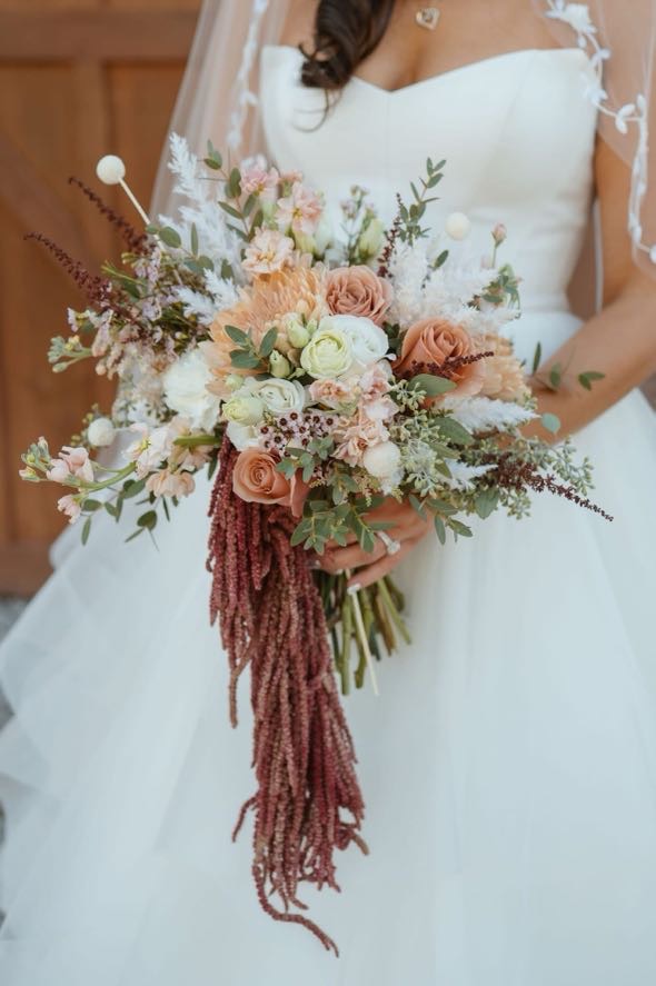 Close-up of cascading bridal bouquet with soft peach and ivory blooms