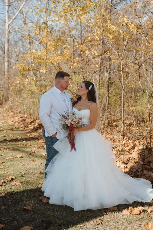 Bride and groom sharing a quiet moment in a forest filled with fall leaves