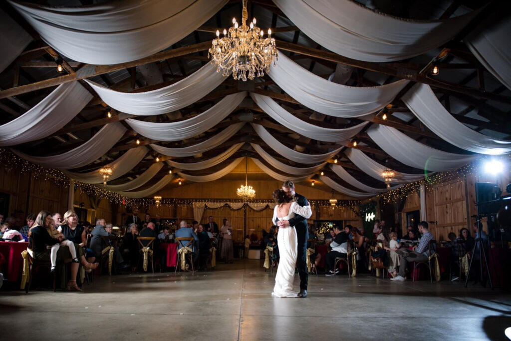 A bride and groom are dancing in a large room at their wedding reception.