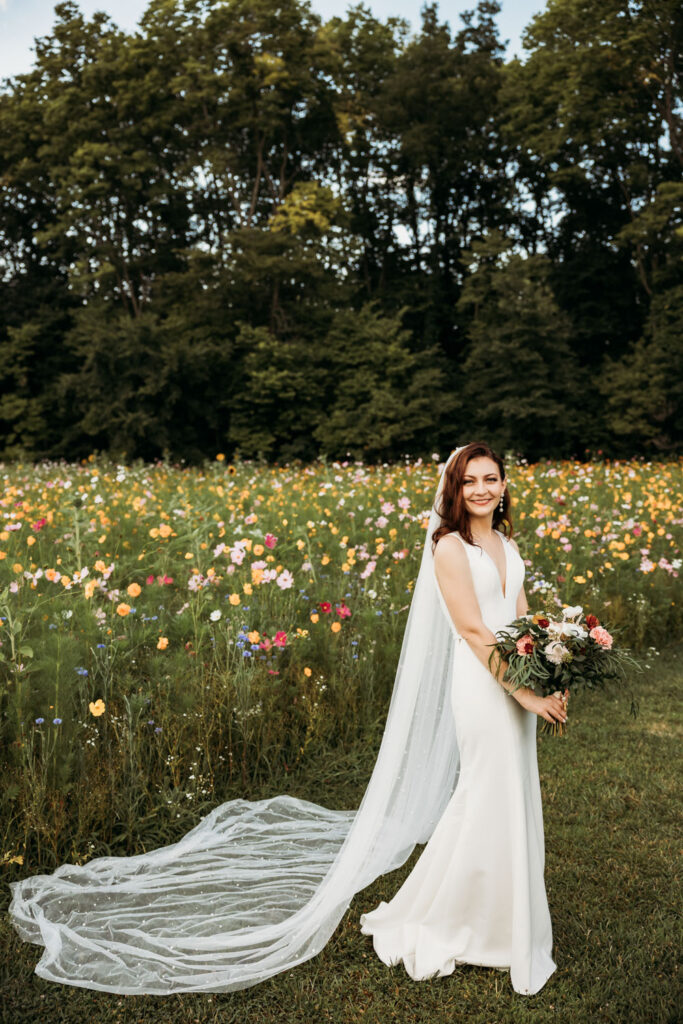 Bride in her flowy lace veil holding her colorful floral bouquet