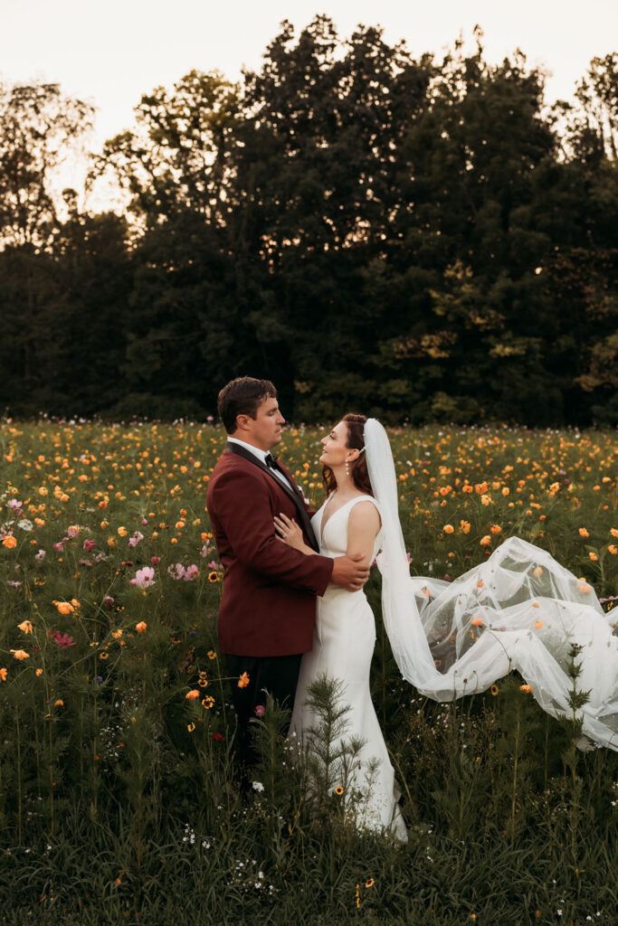 Bride and groom framed by a natural field of wildflowers during golden hour