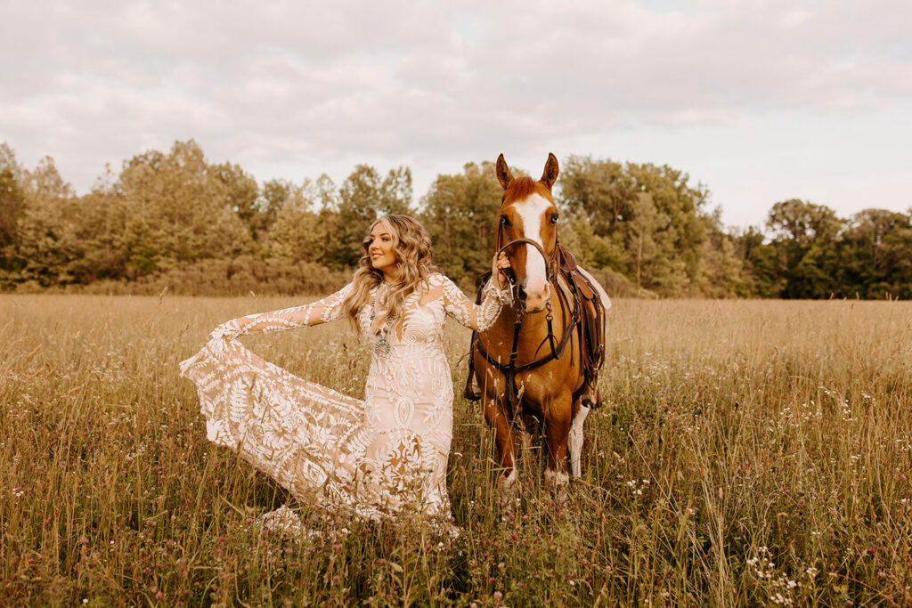 Bride standing beside her horse in a romantic outdoor setting