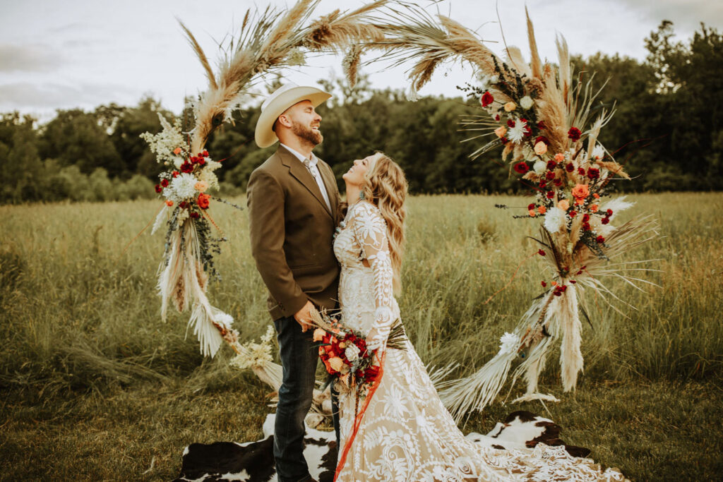 Wildflower wedding portrait of bride in lace gown and groom in tan suit