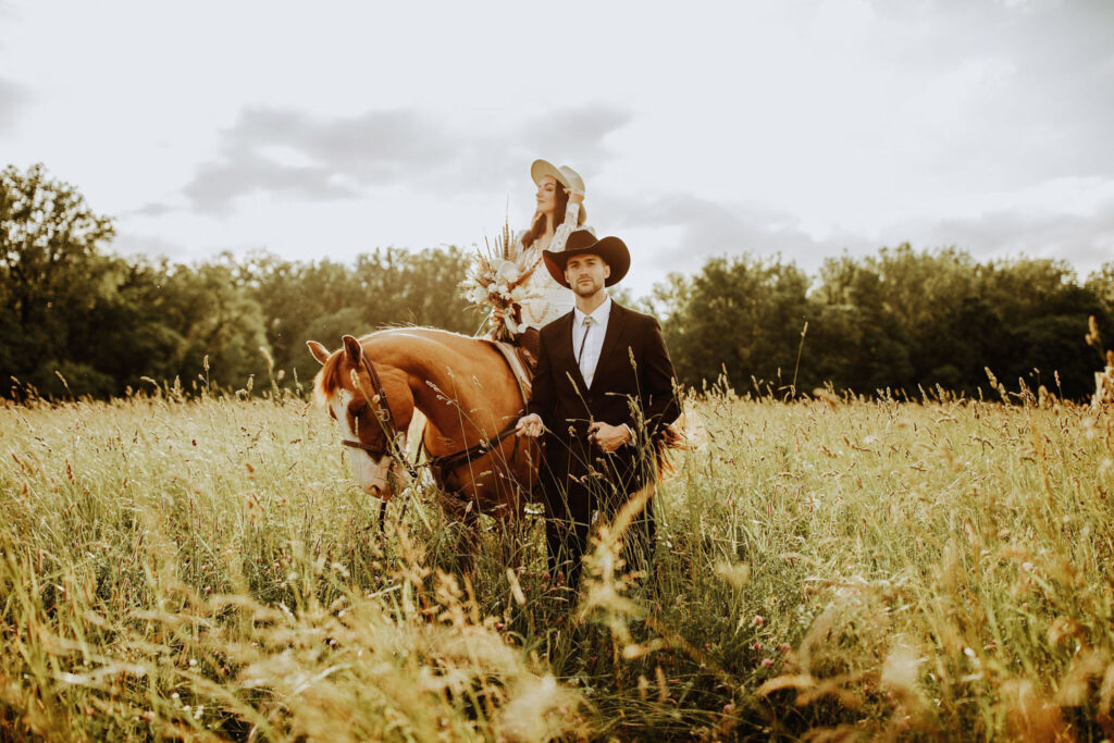Bride seated gracefully on a horse with groom by her side