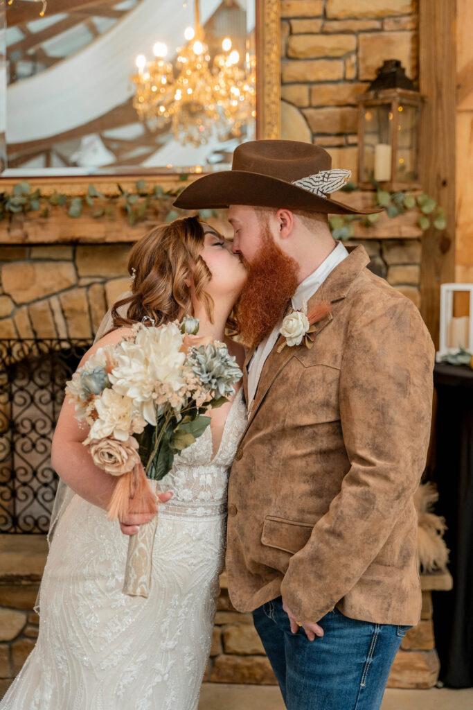 Bride and groom sharing a kiss by the fireplace after their ceremony