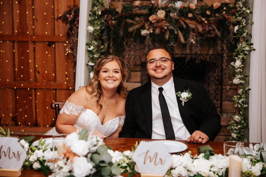 Bride and groom smiling at their sweetheart table