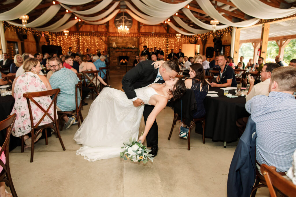 Newlyweds share a kiss on the dance floor surrounded by guests