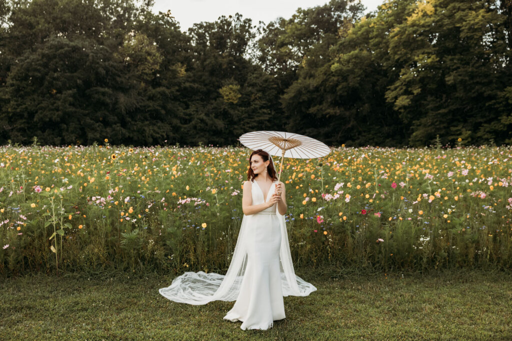 Bride holding an umbrella in front of floral fields of Montgomery Creek Ranch