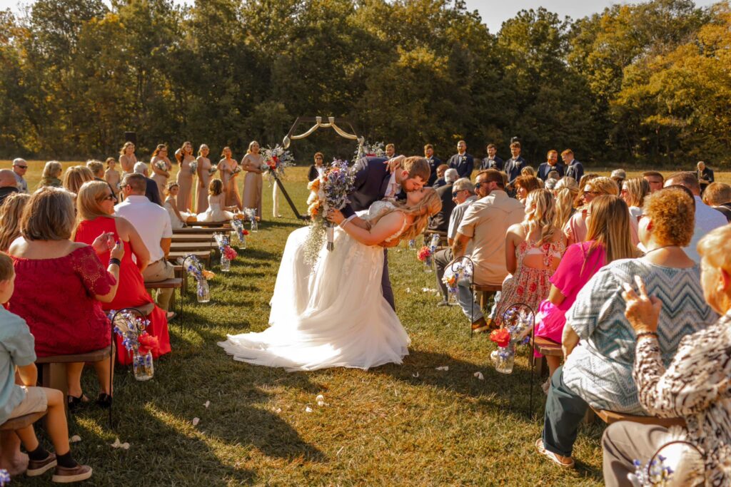 A couple kisses during their outdoor ceremony a moment often prepared in wedding planning 6 months out