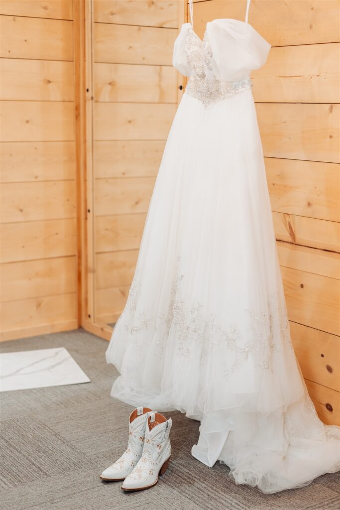 A wedding dress with boots is set up in the bridal suite