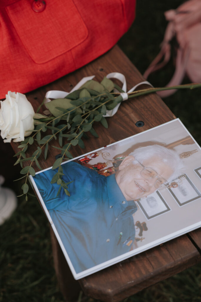 Framed memorial photo and white rose at wedding ceremony