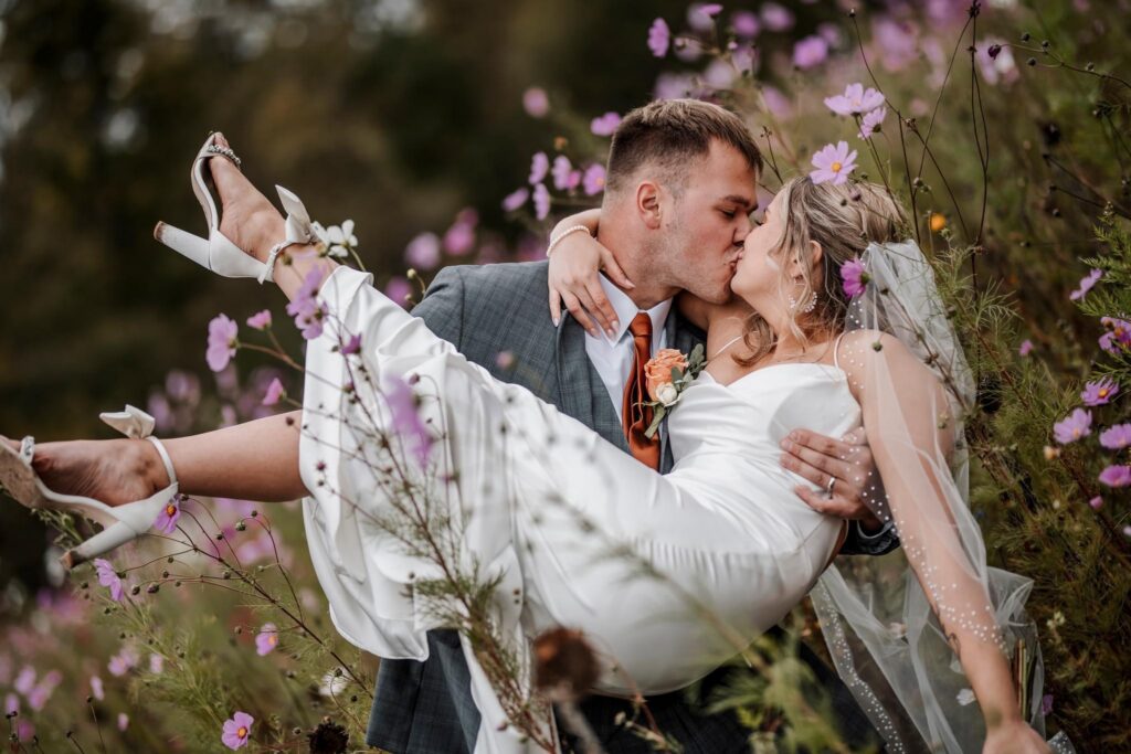 Groom dipping bride in an open field at sunset