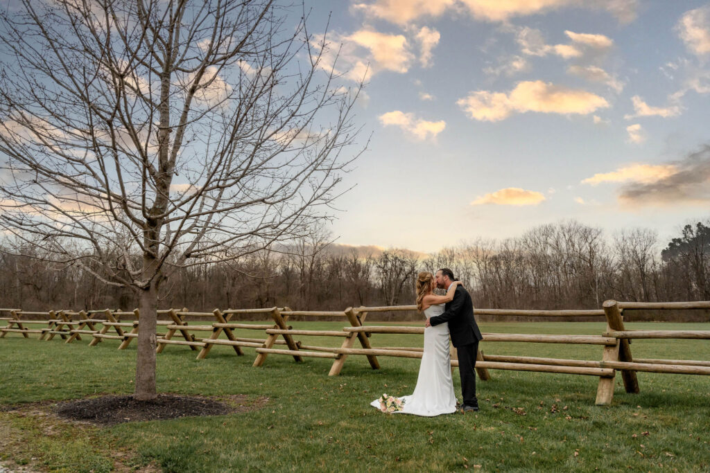 Couple kissing by a wooden fence
